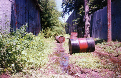 Leaking solvent drums illegally dumped in alleyway.