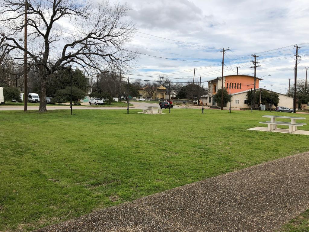 Lawn area with sidewalk in foreground, picnic tables in background and Camacho Center further away