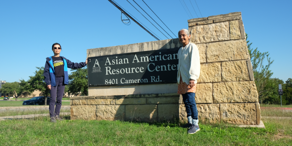 Niki and Himadri stand on either side of the Asian American Resource Center sign.